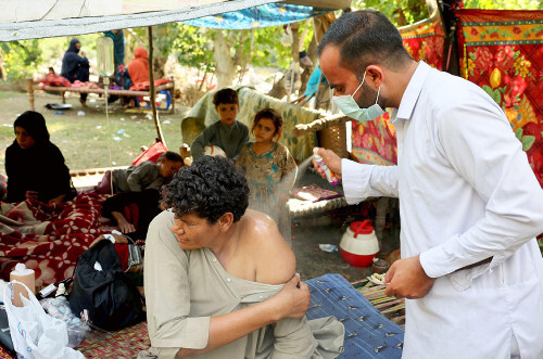 アフガニスタン東部クナール州で負傷したアフガン人男性を治療する医師。厳格なイスラム法が女性被災者の救助を困難にしている現状を示す