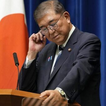 記者会見で辞任の意向を表明する石破茂首相の姿。背後には報道陣が並び、自民党総裁選の行方に注目が集まる。