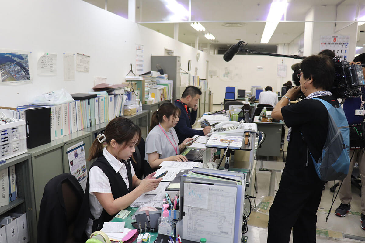 木更津市役所で、アフリカ・ホームタウン騒動に関する抗議電話対応に追われる職員たちの様子。移民政策の誤解が招いた混乱を示す。