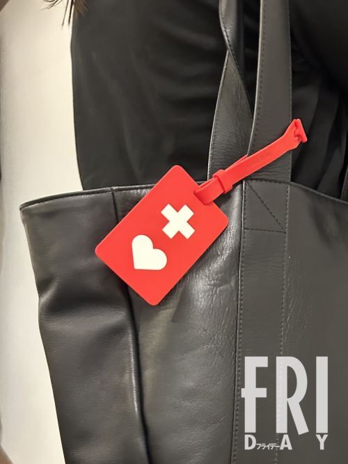 ヘルプマークを持つ若い女性の手元。このマークは、外見からは分かりにくい困難を抱える人が周囲に援助を求めるための目印であり、証明書なしで入手できるため、その利用方法について誤解が広がっている社会問題が提起されています。