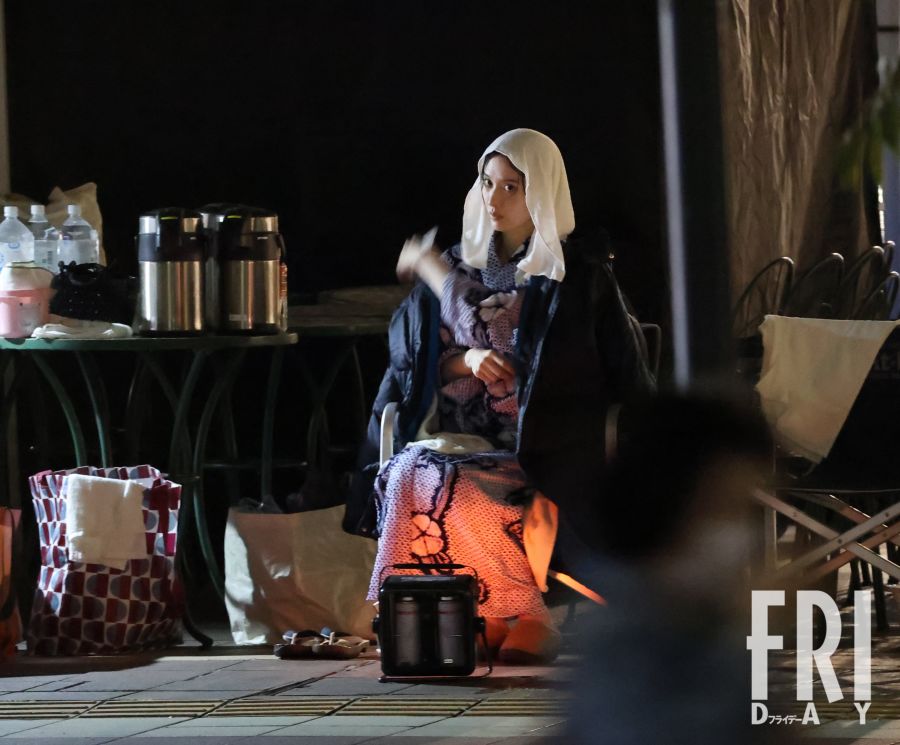 雨中撮影の合間に休憩する月城かなと。浴衣姿にジャンパーを羽織り、強い眼差しが印象的