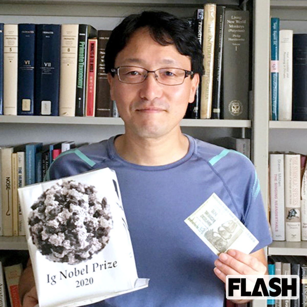 イグ・ノーベル賞:大阪大学・西村剛教授「ワニのドナルドダック効果」受賞後の実情 大阪大学 西村剛教授 イグ・ノーベル賞受賞後 紙製トロフィーとジンバブエドルを手にする姿