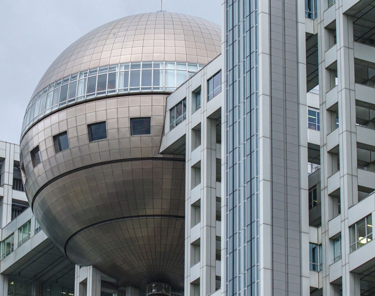 夕暮れ時のフジテレビ本社ビル外観。情報漏洩問題と番組終了で信頼回復が課題となっている様子。