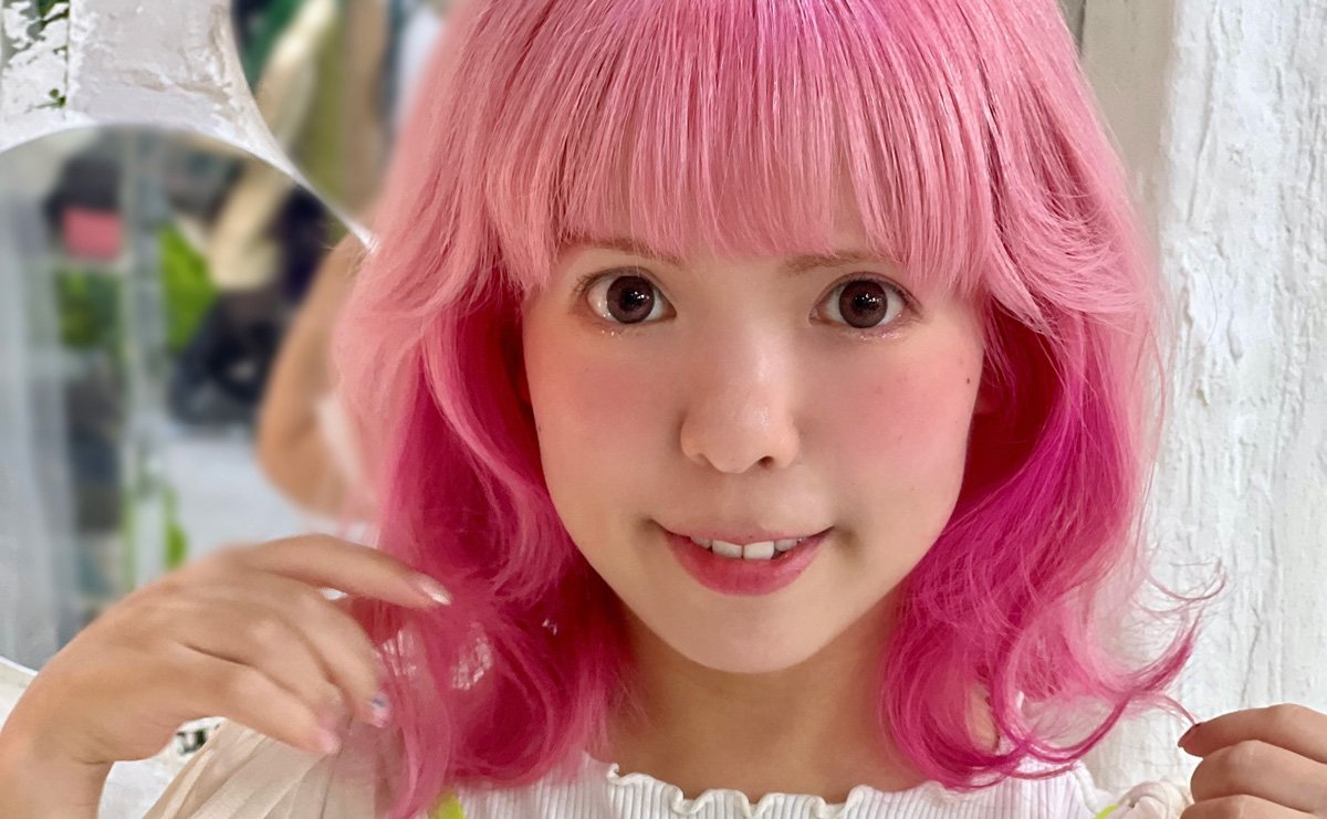 モノクロの背景で笑顔を見せる後藤仁美さん。彼女のファッションセンスが伝わる私服の着こなし。