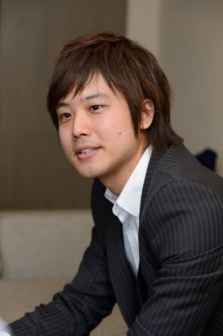 マイクを持つ三浦祐太朗氏。チェック柄以外の服装も似合う