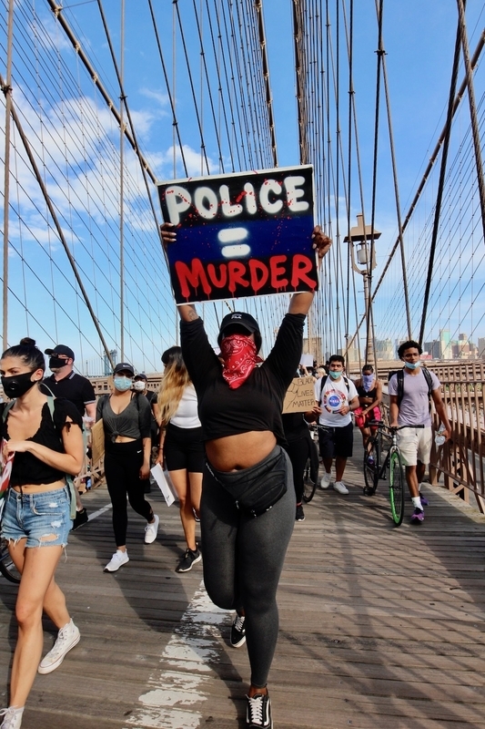 「警察＝人殺し」というプラカードを持つデモ参加者。黒人や人種差別に対する抗議に加え、悪しき警察や司法システムへの抗議も目立った。(c) Kasumi Abe