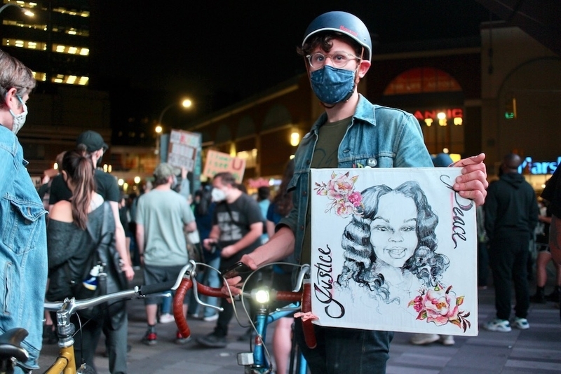 自身で描いたテイラーさんの肖像画持参でデモに参加した人。(c) Kasumi Abe