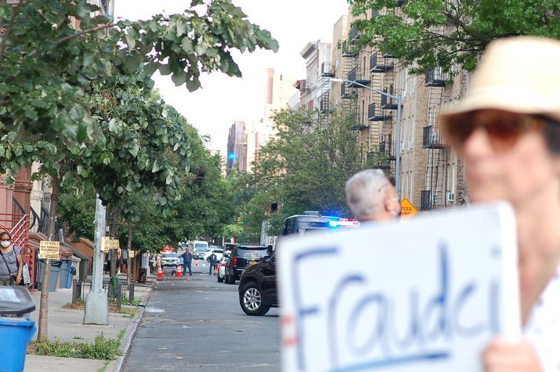 2人の視察中、教会周辺は通行止になった。(右)Fraud(欺く人)とFauci(ファウチ医師)の造語を掲げた人。(c) Kasumi Abe