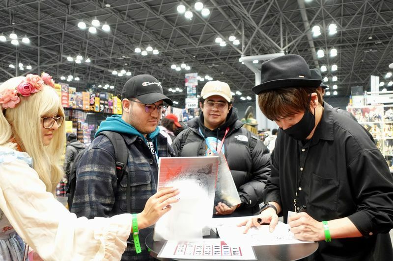 画集の購入者へ、イラストとサインを入れるAcky Bright氏（右）。(c)Kasumi Abe