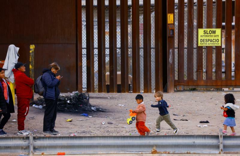今年1月、米・メキシコ国境フェンス付近で難民申請のために並ぶ移民の人々と子ども。