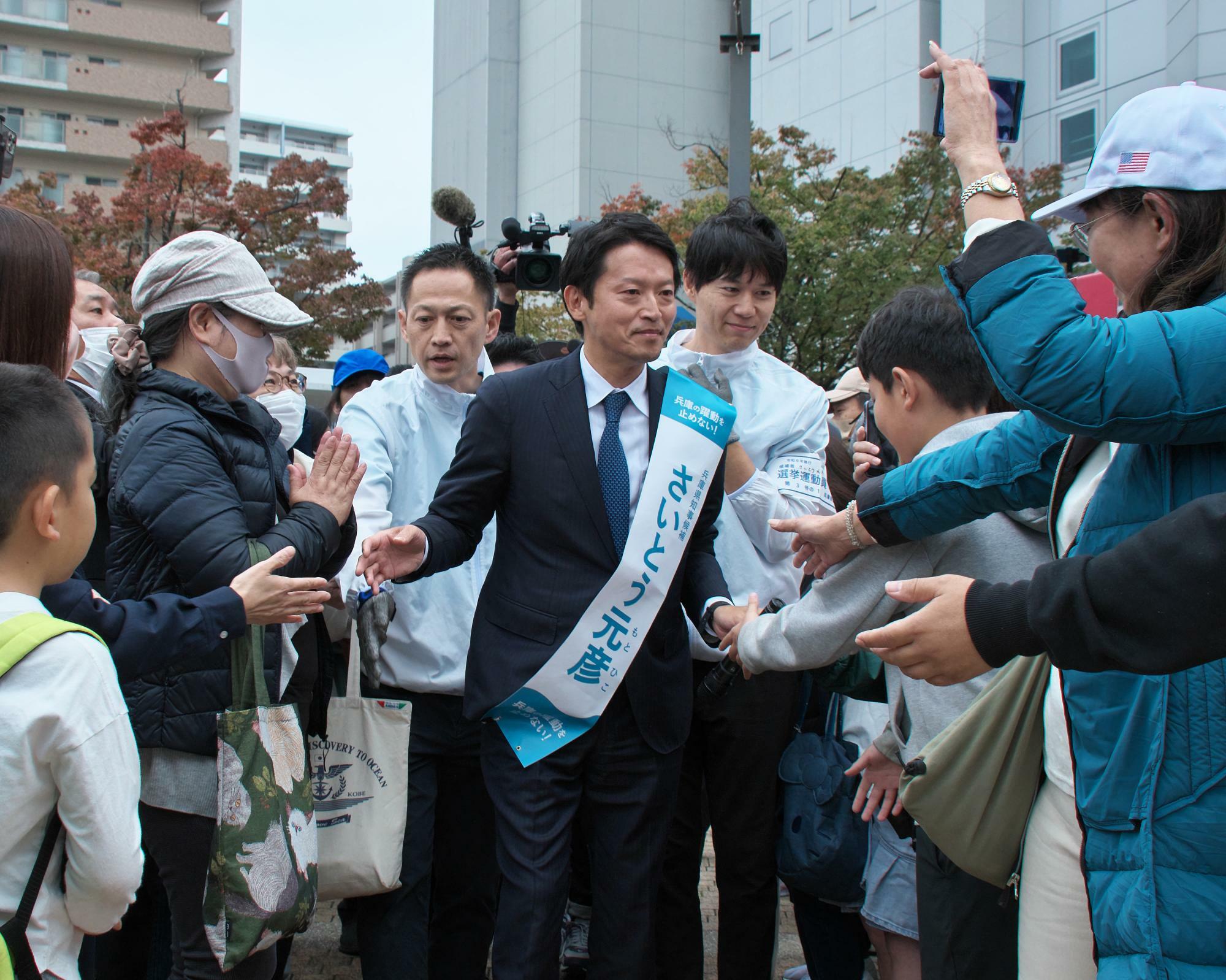 今月16日、選挙演説で支持者と握手する斎藤氏。