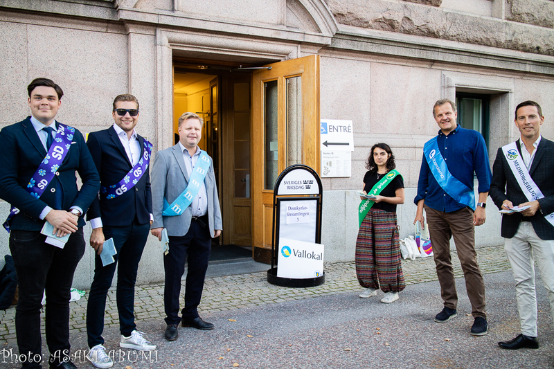 投票会場前では各党の党員たちが立ち、投票直前の人々に無言で選挙人名簿を配布する。写真左側の2人はスウェーデン民主党 Photo: Asaki Abumi