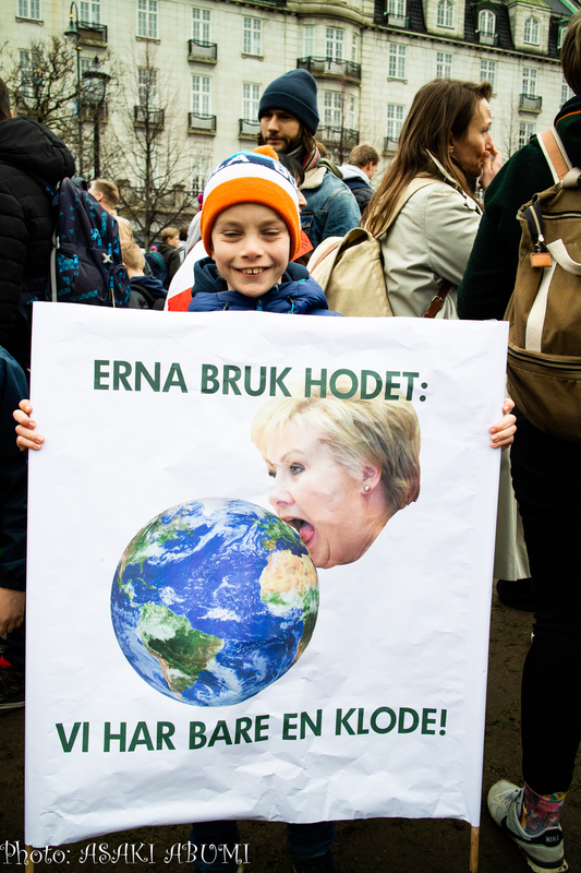 「首相、頭を使ってください」。地球を飲み干しそうなノルウェー首相のイラストを持っていたエーリックさん　Photo: Asaki Abumi
