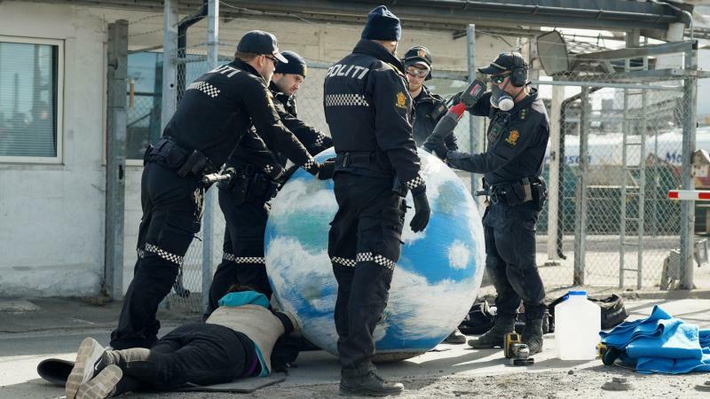 地球儀の中に腕を入れて、現場から離れようとしない活動家たち。連行するために、地球儀を解体する警察官　Photo: Sivil ulydighet #2
