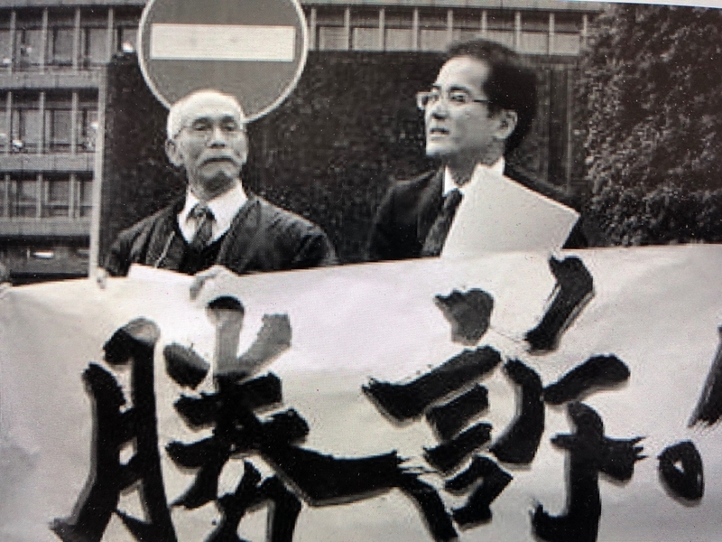 逆転判決を受け大阪高裁前で喜びを語る竹本昇さんと大前治弁護士（提供・大前治弁護士）