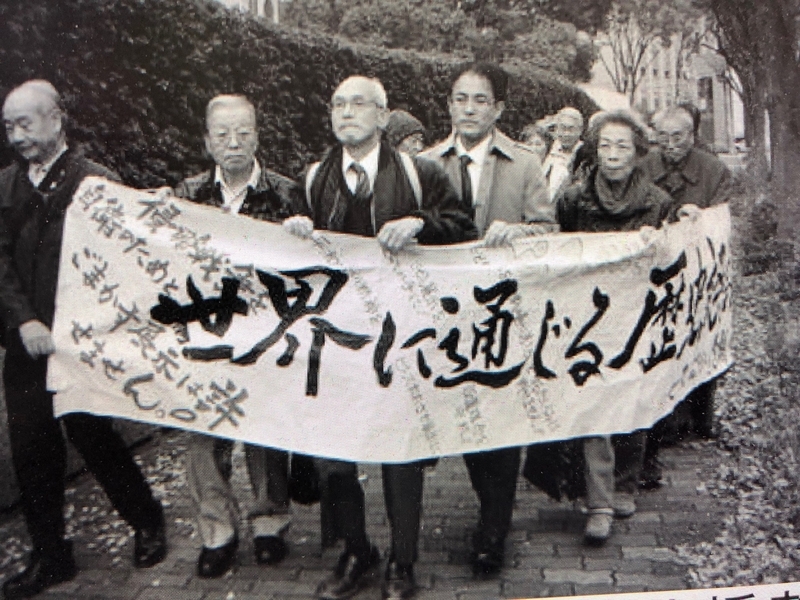 横断幕を掲げ大阪高裁に入る竹本昇さんと弁護士・支援者（提供・大前治弁護士）