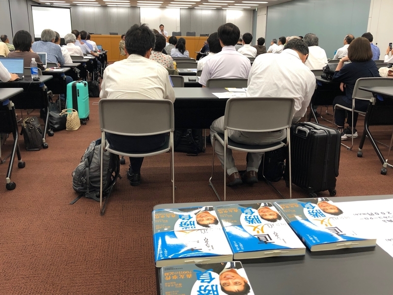 演説会場の後ろに並べられた著書「直及勝負」(撮影・相澤冬樹)