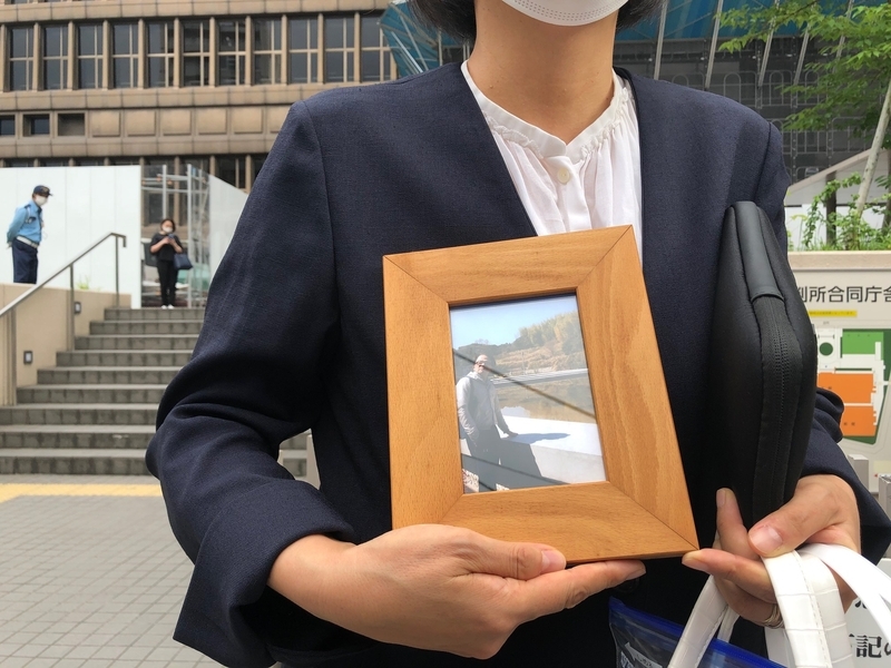 大阪地裁前で夫・俊夫さんの遺影を掲げる赤木雅子さん（筆者撮影）