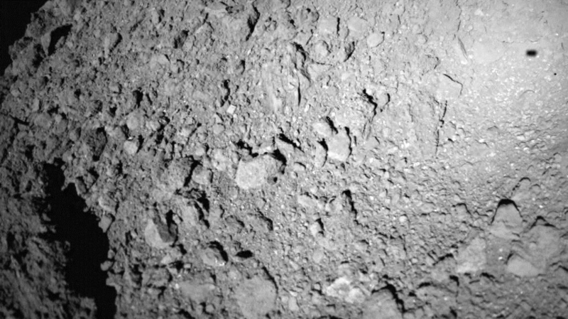 MASCOT着陸機が小惑星リュウグウへ降下中に撮影した画像。右上に着陸機自身の影が写っている。 Credit: MASCOT/DLR/JAXA