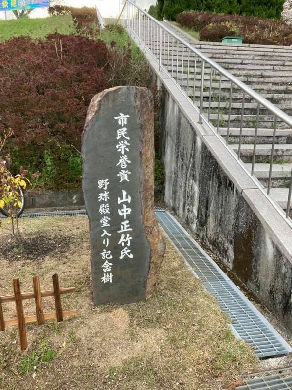 球場のすぐ近くにある地元の英雄・山中正竹氏の野球殿堂入り記念樹を示す石碑(筆者撮影)