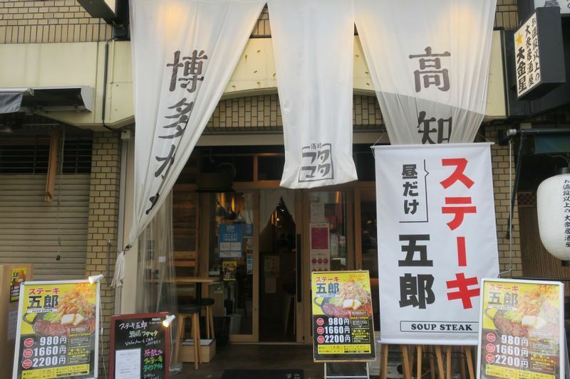 「博多かわ串・高知餃子 酒場フタマタ 西池袋店」の店頭の様子。本来の店の暖簾を目立たなくして、A看板とポスター、のぼりで存在感をアピールしている。（筆者撮影）