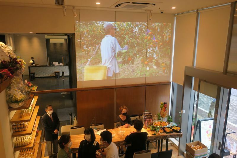 銀座店の店内の壁には和歌山現地の果樹園の様子がプロジェクターによって投影されている。生産者と消費者との距離が著しく近いことが同店の魅力だ（筆者撮影）
