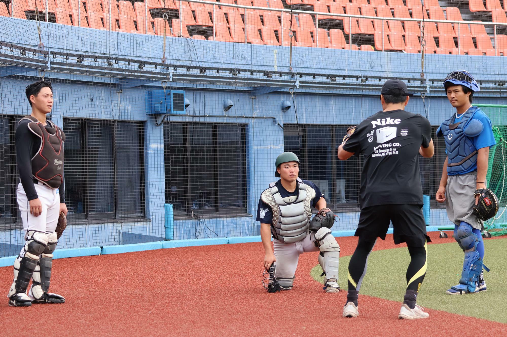 真剣な眼差しで話を聞くキャッチャーズ。（左から）東田汰一、岩室真（ともに富山）、岡崎太一監督、岡村柚貴（ともに石川）