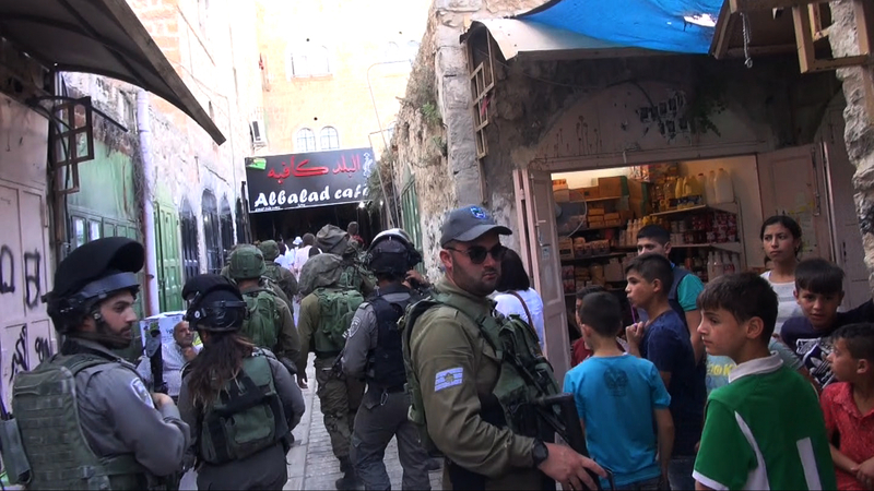入植者たちはたくさんの兵士に守られながら、スークのパレスチナ人住民の中を練り歩く。