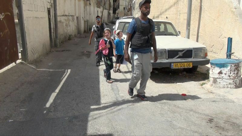 ユダヤ人入植者の子どもたちが武装したガードマンに守られ、シルワンの街中を移動する（撮影・土井敏邦）
