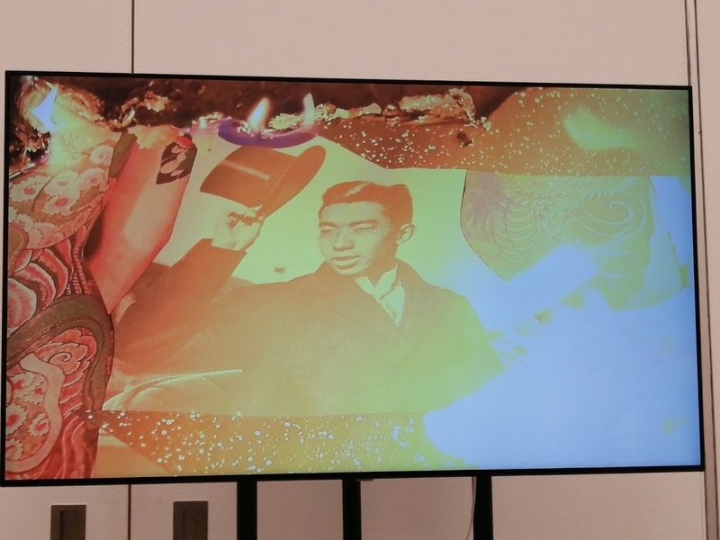 焼かれているのは大浦さんのコラージュ作品。新作の20分ほどの映像作品は、大きなスクリーンでゆったり見ることができるように展示の仕方が変更された