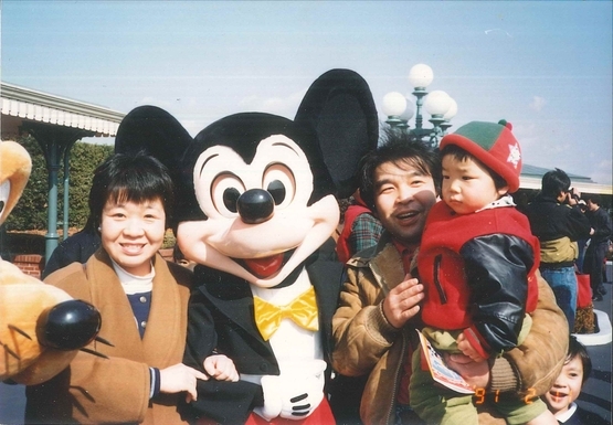 ディズニーランドで笑顔の幸子さん（左）と長男を抱いた一雄さん（1991年2月、遺族提供）