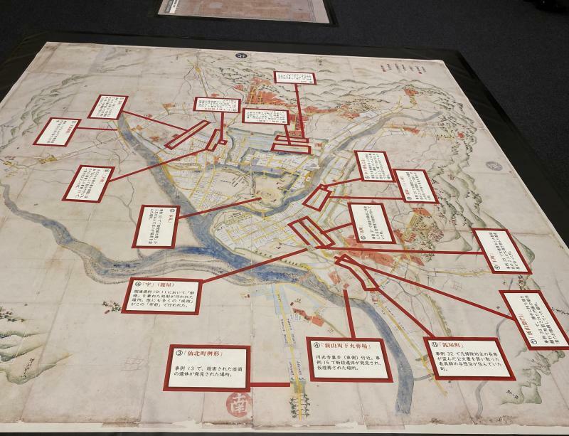 大判の当時の地図が床に貼られ、事件が起きた場所を示しているほか、刑場のあった場所や追放先などを示した地図なども展示されている。