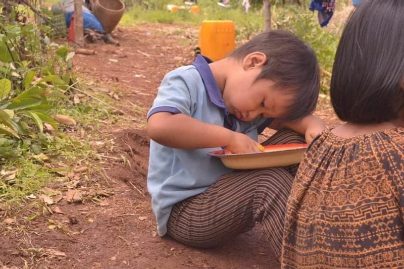 地面に座りコメを食べる少年（ミャンマー東部カヤー州、現地からの提供写真）