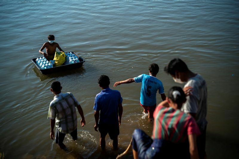 ミャンマー国軍と抵抗勢力の戦闘が激化し、国境沿いの川岸に逃れ、タイ側から運ばれる支援を受け取る避難民ー2022年１月７日