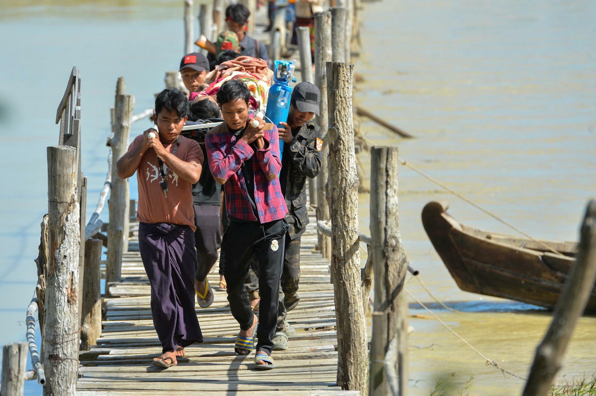 ミャンマー・ザガイン管区近くで、負傷者を運ぶ人々＝2023年11月23日