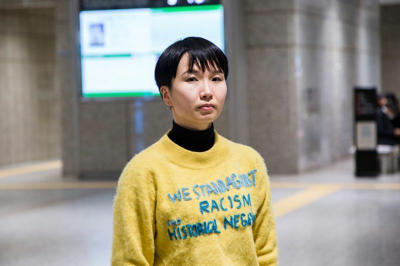 東京都人権部に要望書を提出した日のニットには、飯山さん自身による「WE STAND AGAINST RACISM AND HISTORICAL NEGATIONISM」という刺繍が（写真：金川晋吾）。