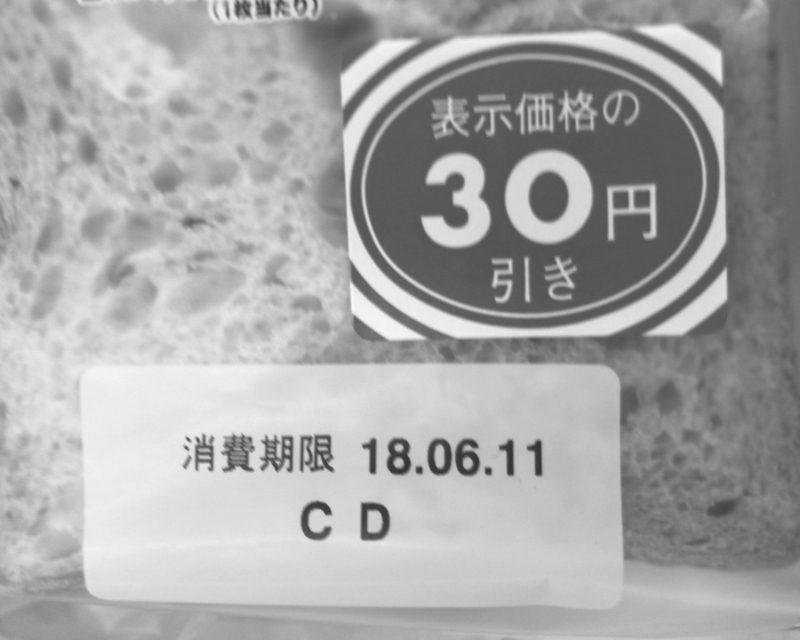 売価より30円引きの見切り販売しているパン（筆者撮影、白黒加工）
