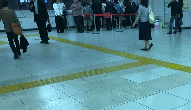 2018年10月17日18:30過ぎのJR赤羽駅、1・２番線ホームに上がる階段と「QB HOUSE」の間で入店の順番待ちをする人々（筆者撮影）