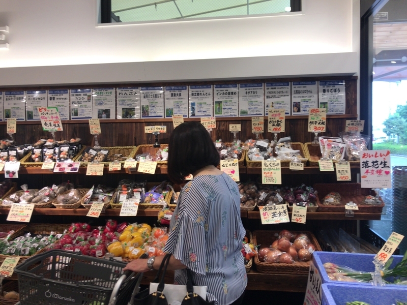 群馬県高崎市のスーパーまるおかの野菜コーナー。生産者の名前と顔写真が貼ってある（筆者撮影）