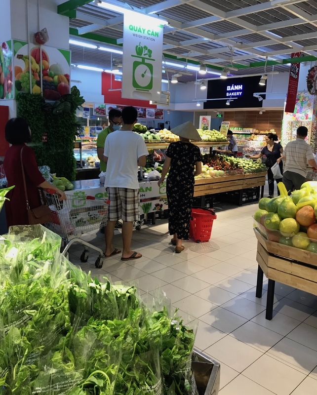 ベトナム・ハノイのBig Cスーパーマーケットの野菜売り場。量り売りで、量ってくれる店員のところに顧客が並んでいる（筆者撮影）