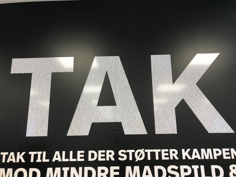 店内の壁に掲げられた「TAK（ありがとう）」の白抜きの文字の中には貢献者の名前がびっしり書かれている（筆者撮影）