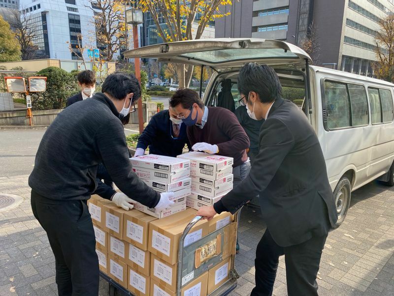 2020年12月18日、賞味期限の過ぎた果物缶詰を含む備蓄食品を、福島県の福祉団体の車に積みこむ農林水産省の職員の方々（筆者撮影）