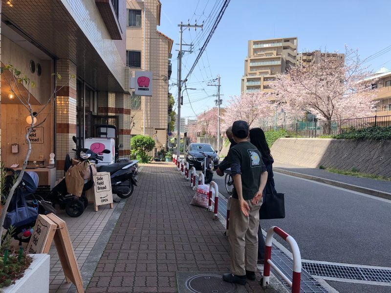 灘駅、もしくは岩屋駅、どちらの駅からも歩いてすぐのところ、桜並木の脇に店舗がある。手前に立っているのがオーナーの横畠さん、向こう側が山下誠一郎さん、真ん中が筆者（撮影：大田美月氏）