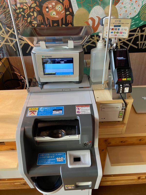 コンタクトレス会計の機械。カードなら右手の機械にカードを挿入、あるいはタッチし、現金なら手前のところからお札と小銭を投入する。店員とのやり取りは不要(筆者撮影)