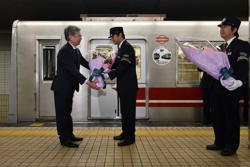 最終列車に乗務した運転士と車掌に、交通局長から花束が手渡された