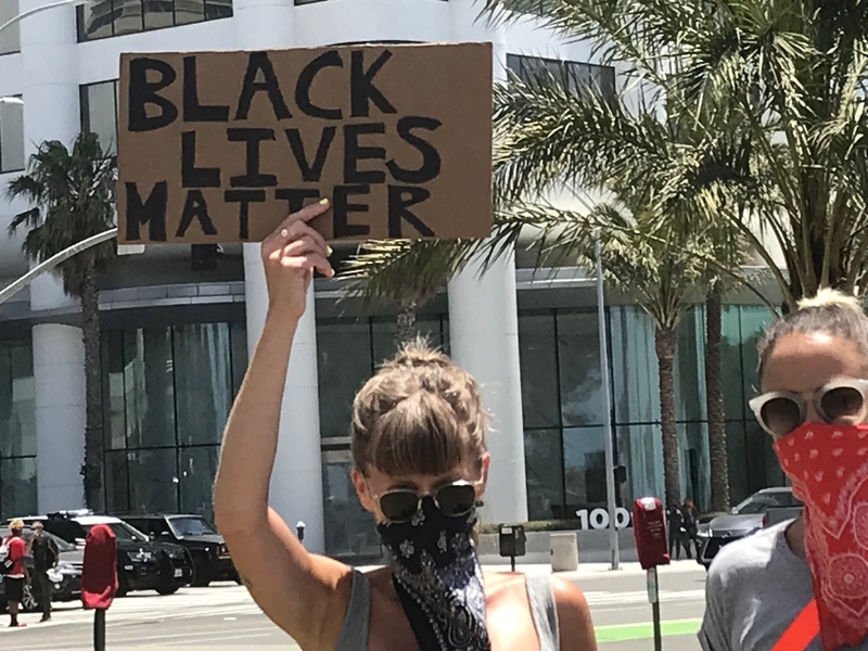 Black Lives Matterと書かれたボードを高く掲げる女性。筆者撮影