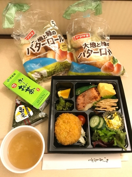 ホテルで1泊目の夜に提供された夕食。ロールパン2袋、おかずのパック、おにぎり1個、お茶、味噌汁と十分な量である。筆者撮影