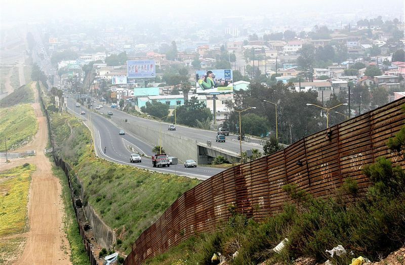 昔建てられた国境の壁の中には、とても壁とは呼べない粗末なものも多い。錆びて茶色くなった壁の向こう側にはメキシコの街が広がる（米カリフォルニア州、2006年、筆者撮影）