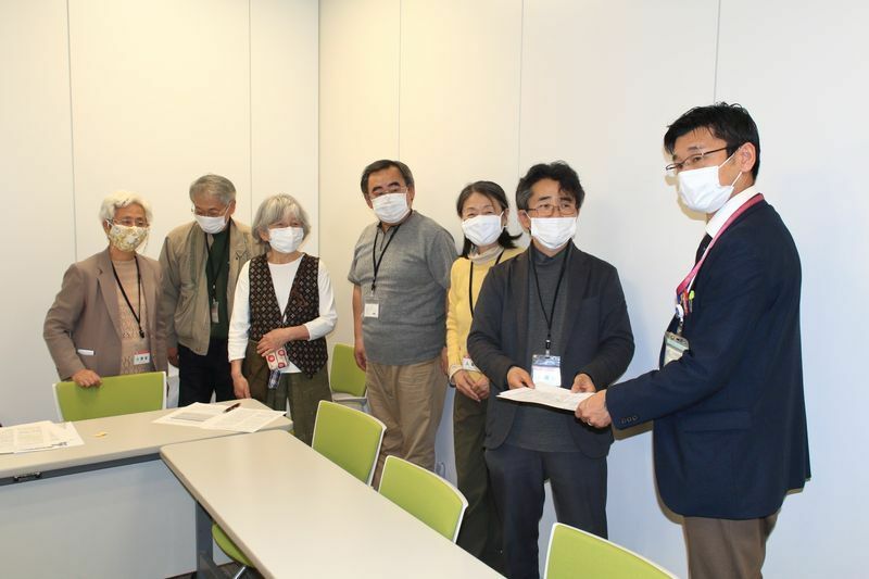 4月2日、横浜市役所の会議室で健康福祉局精神保健福祉課の課長へ「横浜市依存症対策地域支援計画（仮称）」素案に対するパブコメを手渡すKACAのメンバー。写真撮影筆者