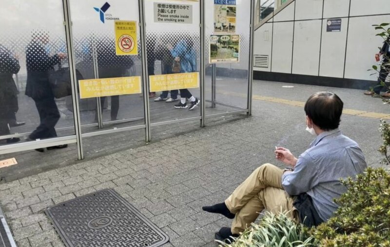 横浜市内の公衆喫煙所。喫煙所内は臭いからと外で吸う人も多く、周囲にはポイ捨てされた吸い殻も目立つ。写真撮影筆者